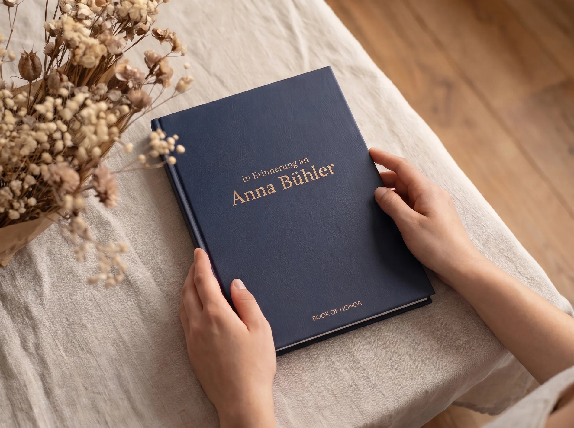 Hände halten das Book of Honor Erinnerungsbuch mit goldenem Namensdruck